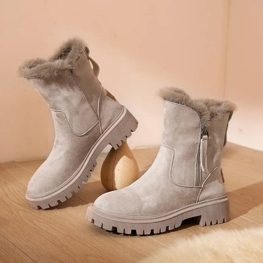 Beige suede boots with fur trim on a wooden floor