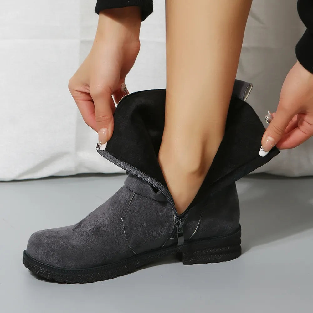 Person putting on a gray ankle boot with a zipper