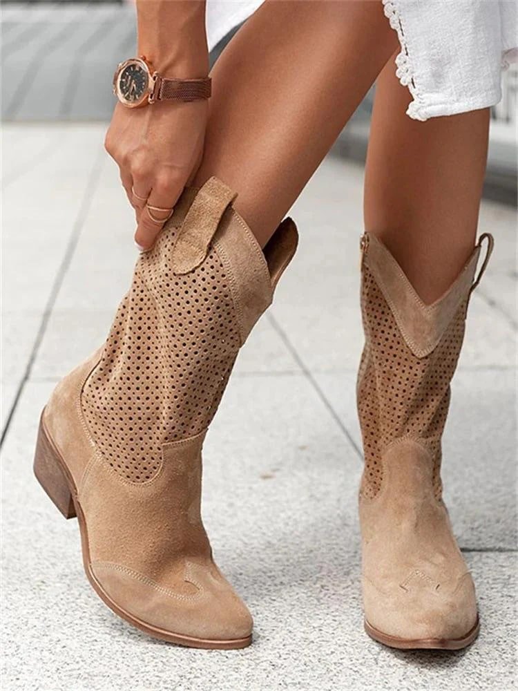 Tan cowboy boots worn by a person on a light background