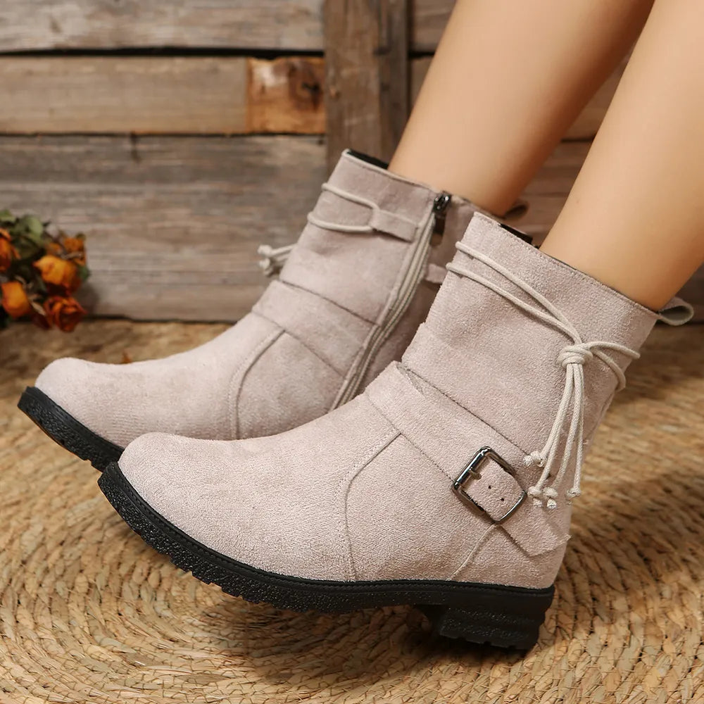 Beige ankle boots with a buckle on a woven surface