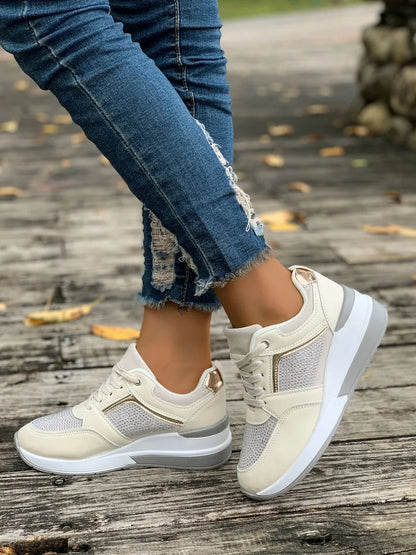 Beige sneakers worn with blue jeans on a wooden floor