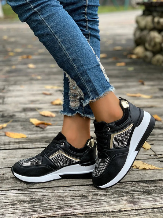 Black sneakers with rhinestone details worn with ripped jeans on a wooden floor