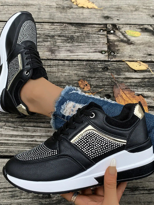 Black sneakers with white soles on a wooden floor