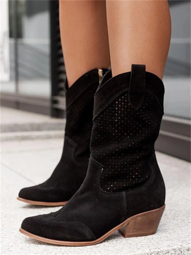 Black suede cowboy boots with wooden heel on a blurred background