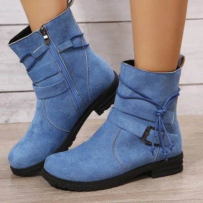 Blue ankle boots with black soles on a wooden floor