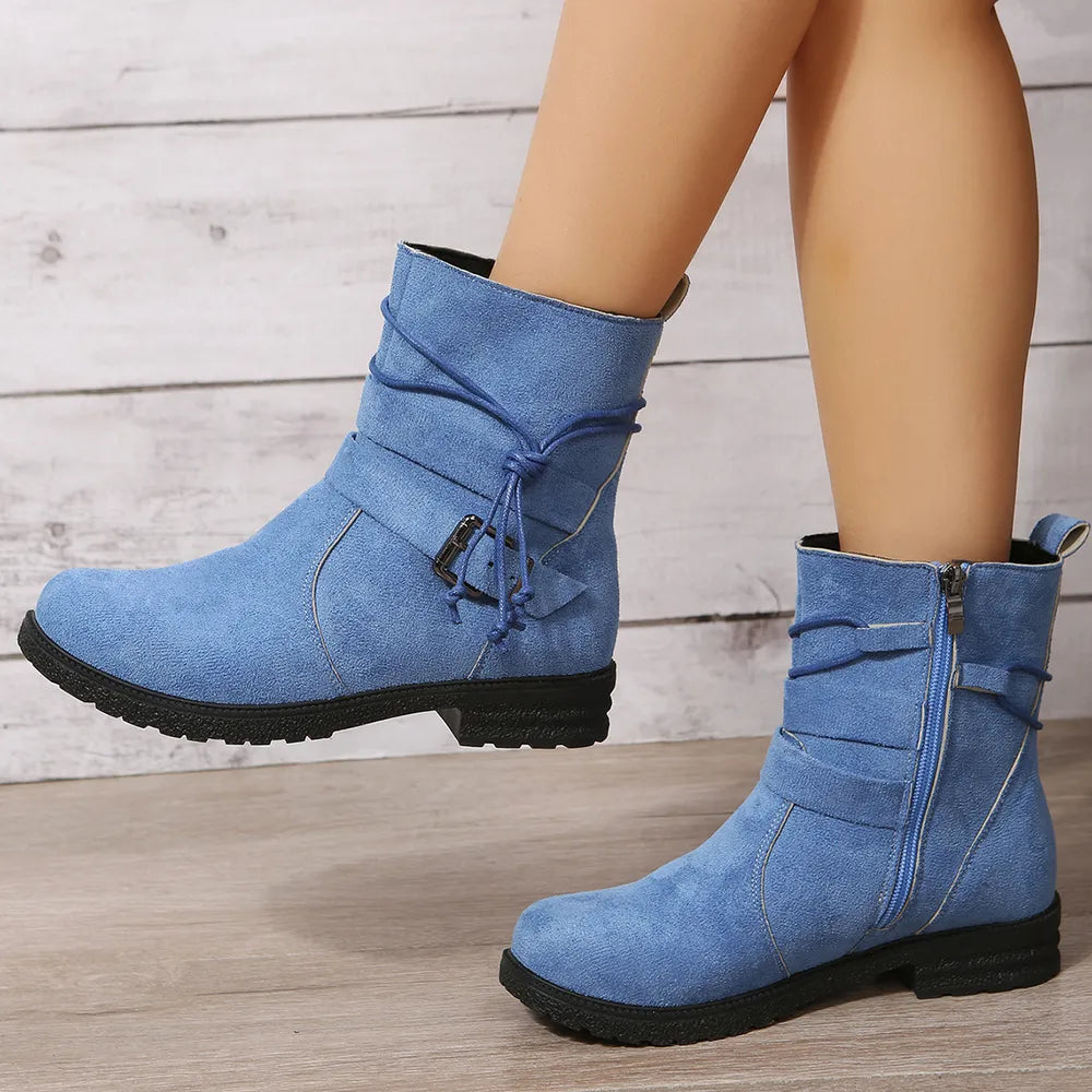 Blue denim boots with black soles on a wooden floor
