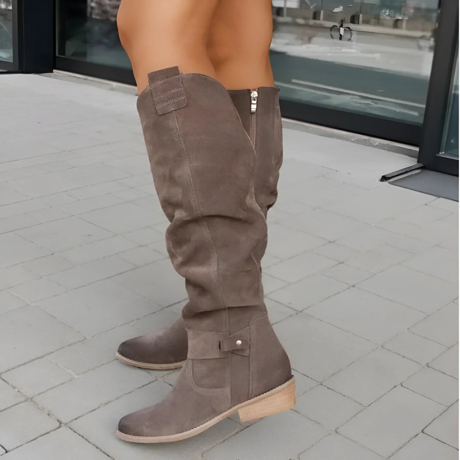 Brown knee-high boots on a person standing on a tiled pavement
