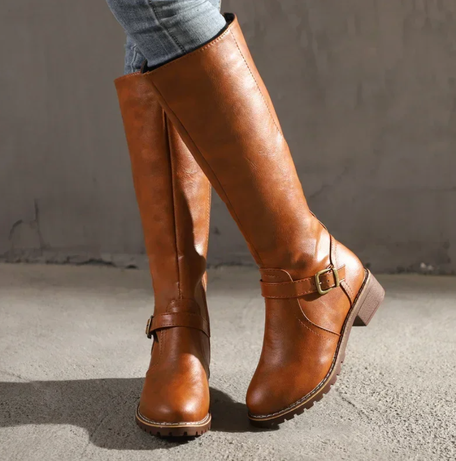 Brown knee-high boots with a buckle on a neutral background
