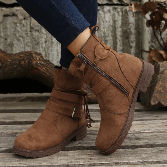 Brown suede boots with a zipper on a wooden surface