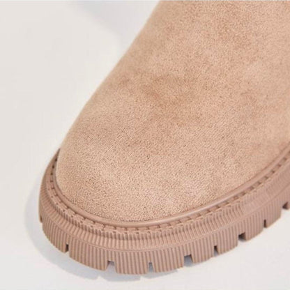 Close-up of a beige suede boot with a white sole on a light gray background