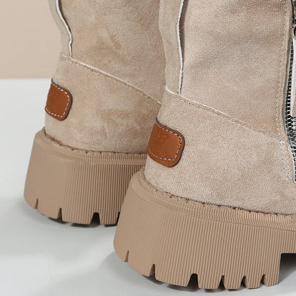 Close-up of beige suede boots with brown accents on a light gray background