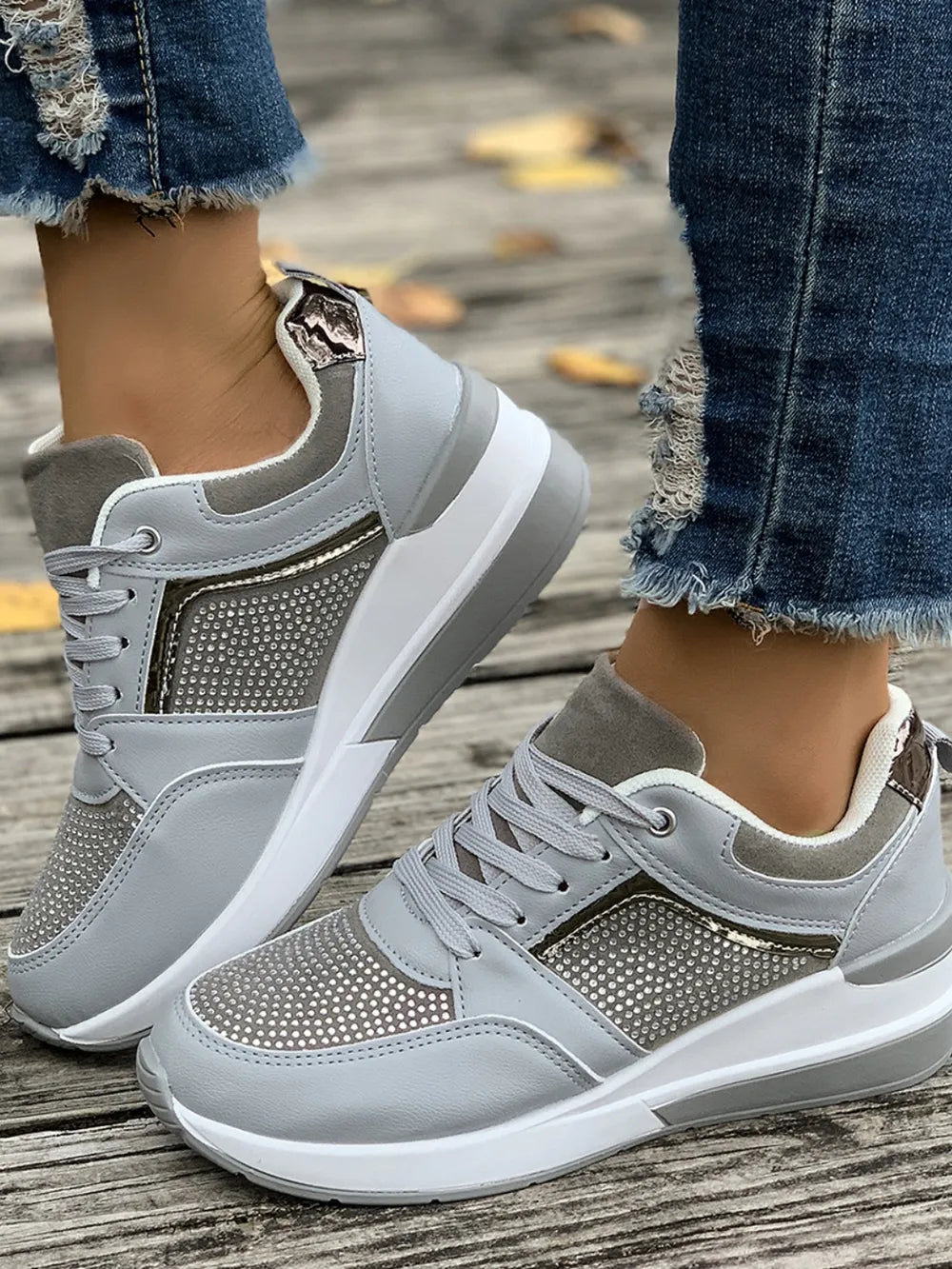 Gray and white sneakers worn on a wooden floor