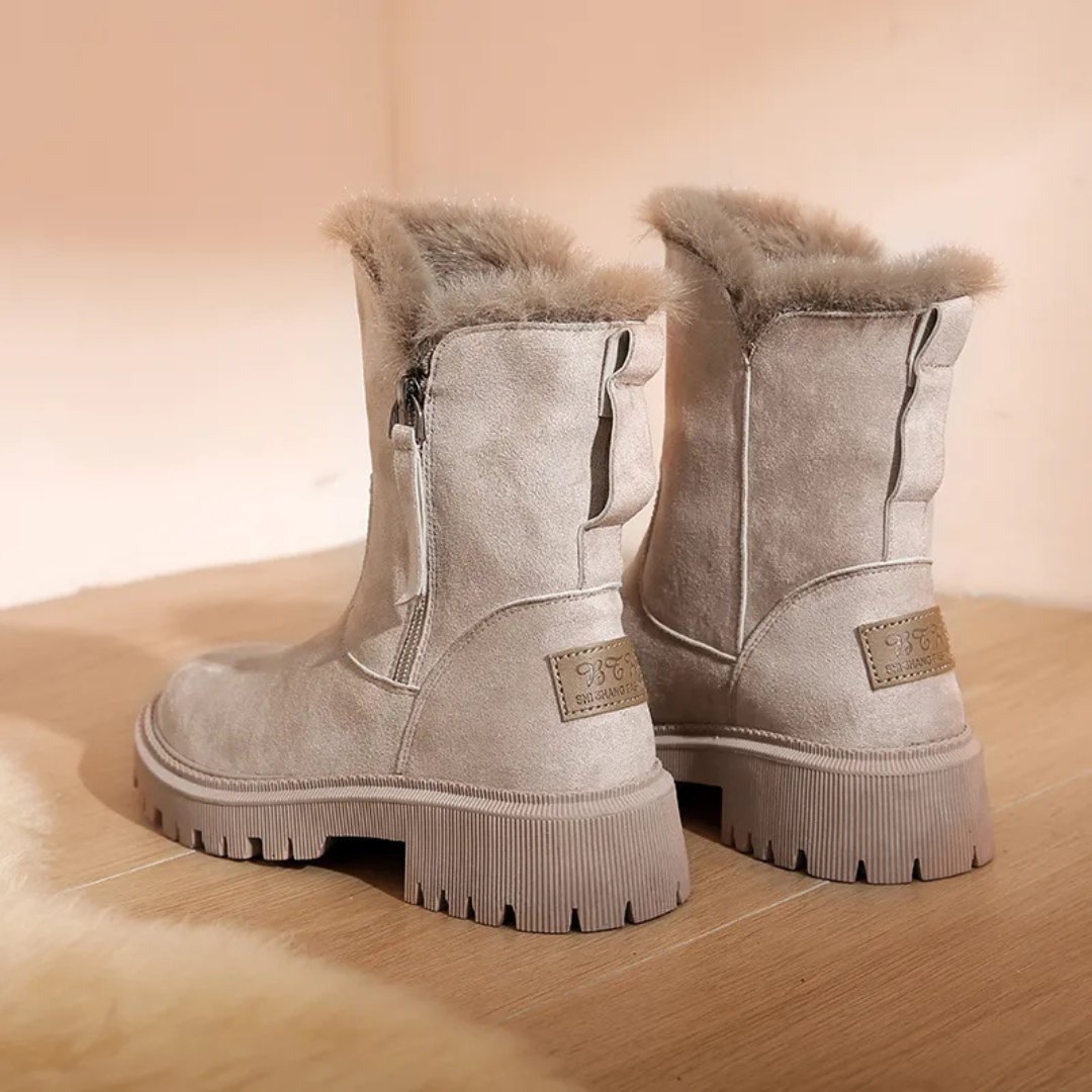 Pair of gray suede boots with fur lining on a wooden surface