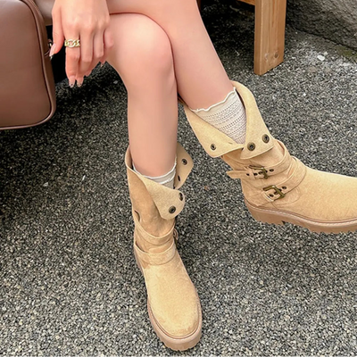Person wearing beige boots sitting on a bench with a neutral background