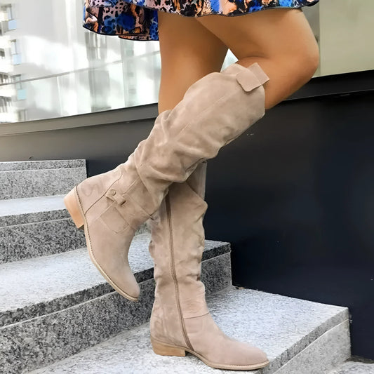 Person wearing beige knee-high boots on a staircase