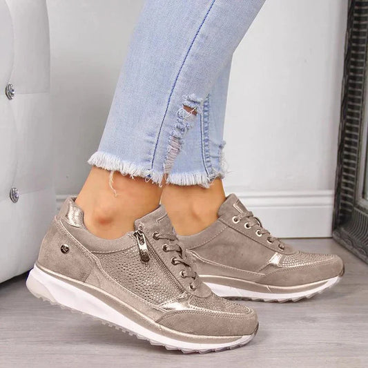 Person wearing beige sneakers with white soles on a neutral background