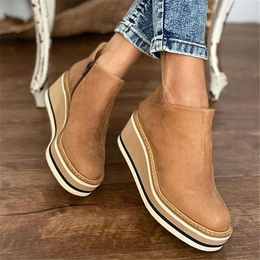 Tan platform shoes worn with rolled-up jeans on a wooden floor